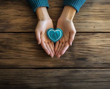 A motivational International Volunteer Day composition with a pair of open hands and a heart shaped emblem resting on a wooden table, macro shot, Minimalist style